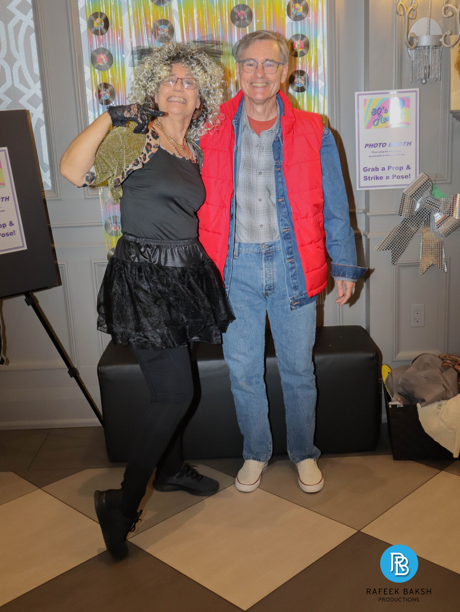 Smiling couple at the photobooth wearing 80s themed clothing at the 2025 Emajjin gala