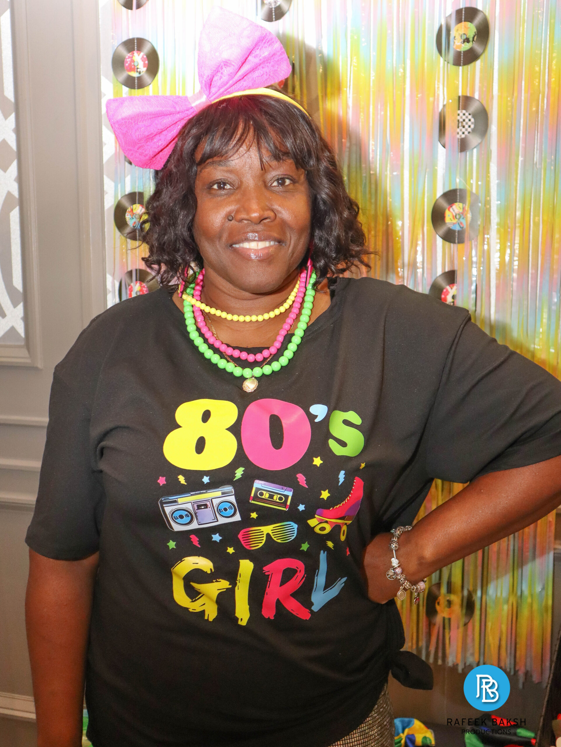 Woman wearing an 80s girl tshirt and a big headband posing at the photobooth at the 2025 Emajjin gala