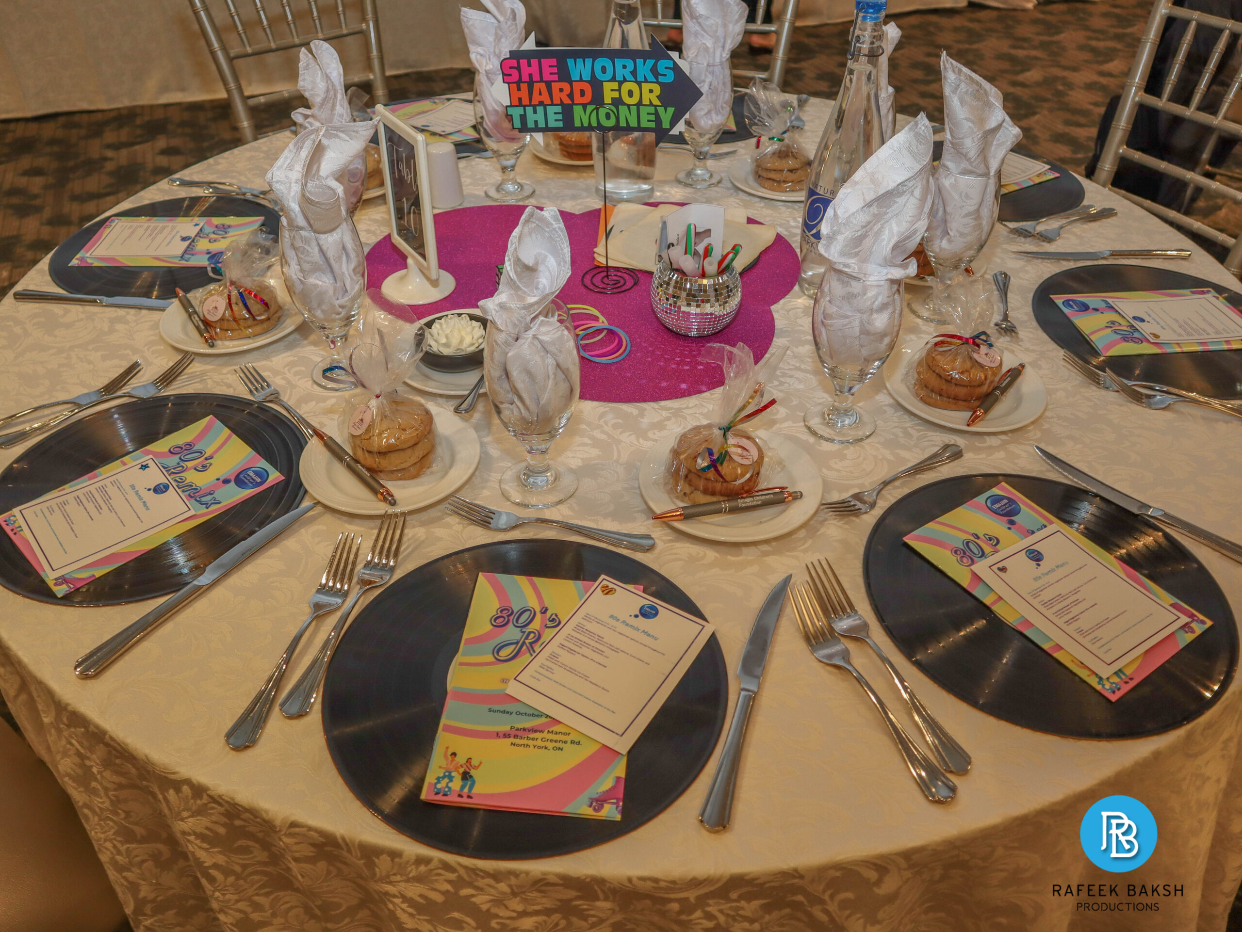 Table setting at the 2025 80s Remix Gala showing 80s themed decor, menus, programmes and favours