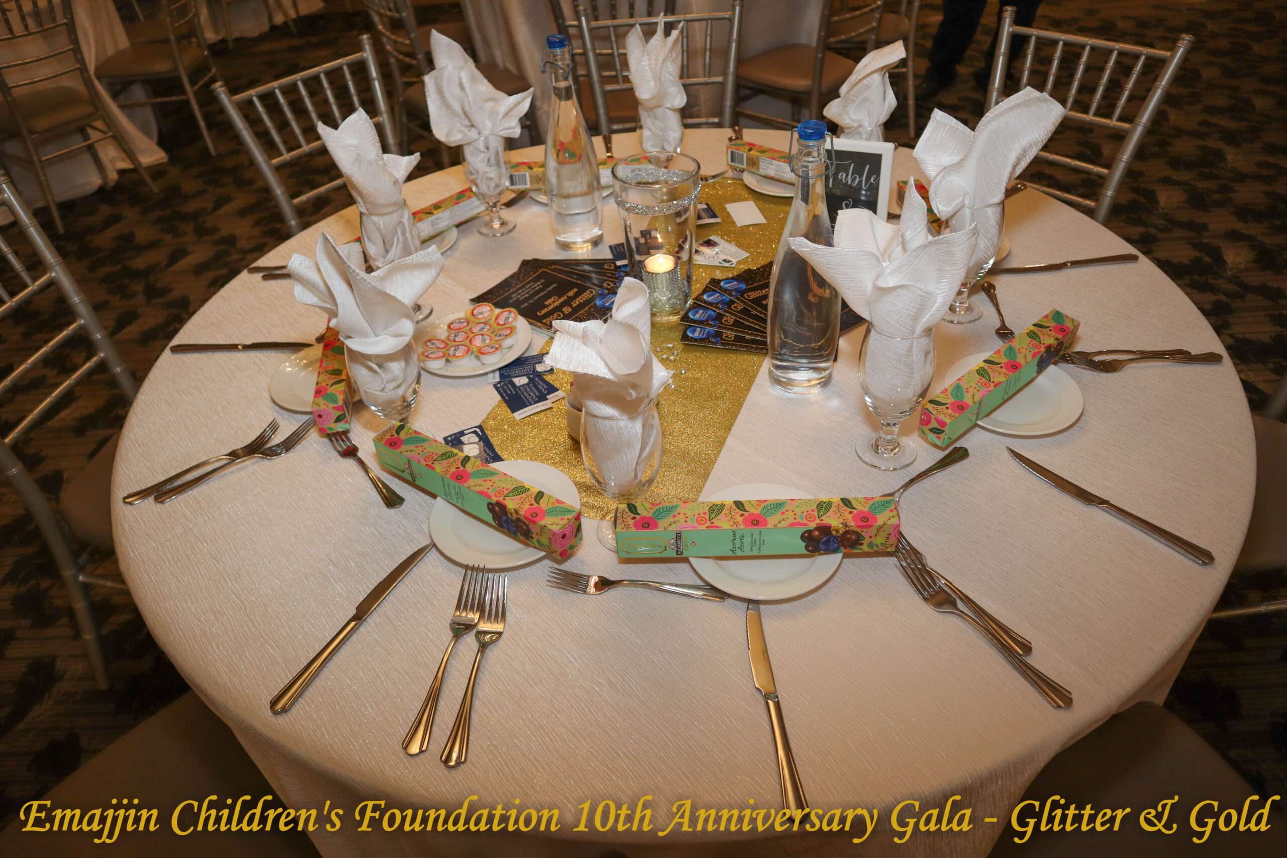 table setting at the 2024 Emajjin Gala showing programmes, favours and themed decorations