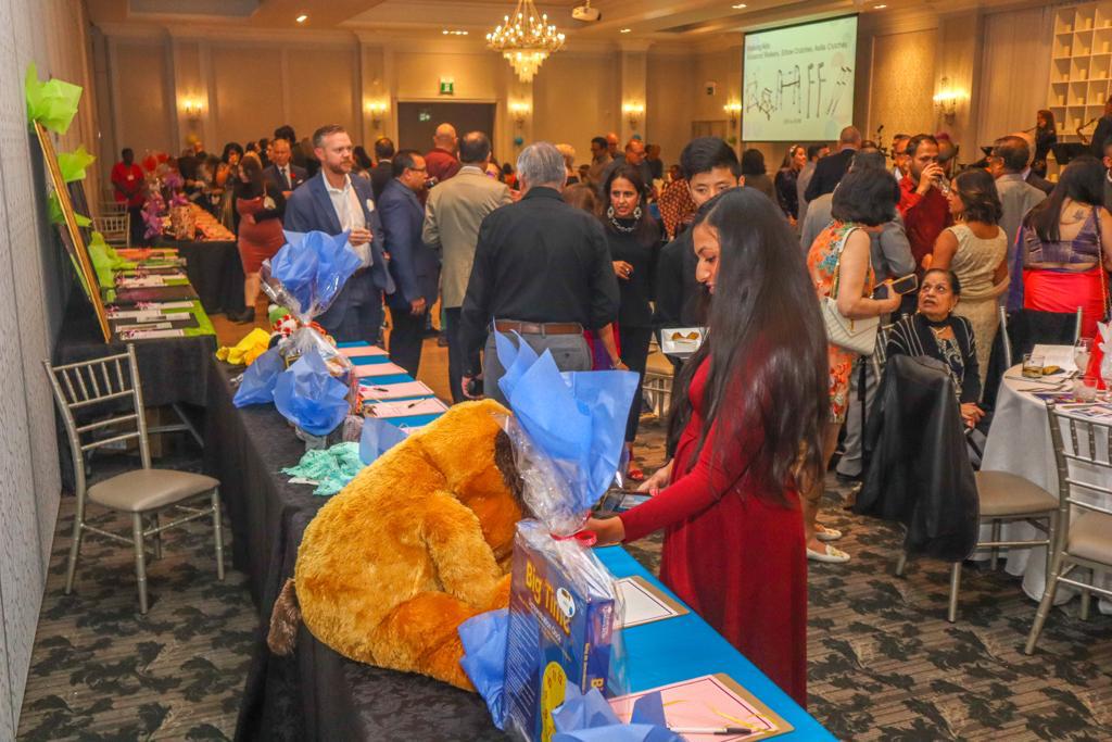 A woman browsing silent auction items at the 2022 Emajjin Celebration gala against a backdrop of a crowded room
